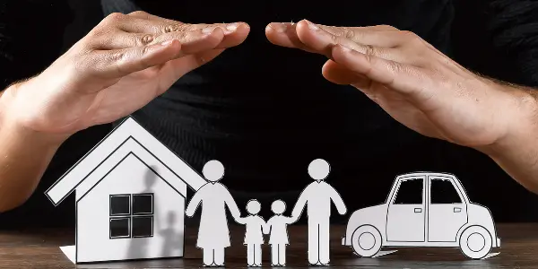 image de deux mains qui protègent une maison et une famille constitué d'un homme, une femme et des enfants grâce à une assurance emprunteur sur le bilan de deux ans de la loi lemoine