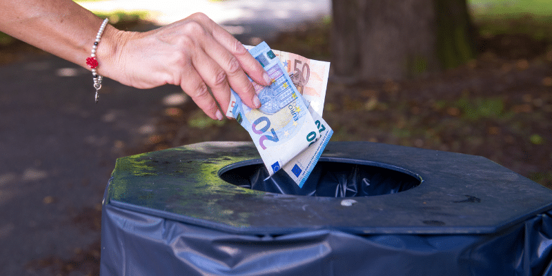 Prêt immobilier évitez les mauvaises dépenses. image de jeter l'argent à la poubelle.