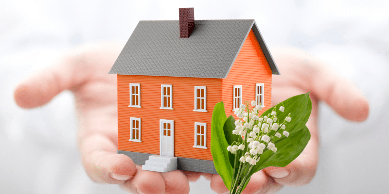 Une maison orange acquise avec un prêt immobilier et un muguet pour représenter MAI 2024