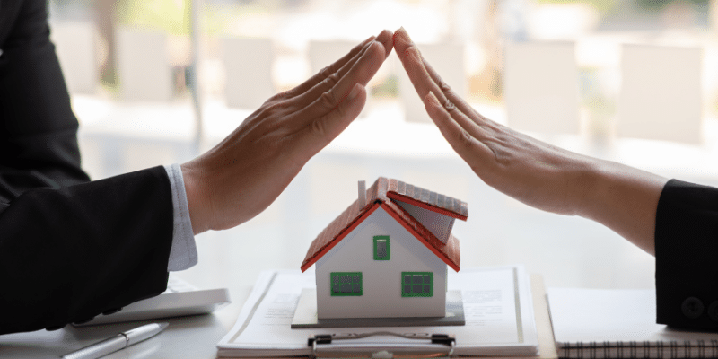 deux mains forment un toit sur une maison pour illustrer les prêts immobiliers en juin 2024